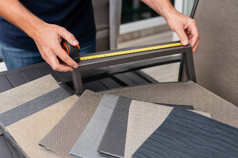Custom Sling Order: 7 Ultimate Secrets to a Flawless... 4 Custom Sling Order - Close-up of hands accurately measuring patio chair frame for a custom sling order, with fabric swatches and a tablet showing online ordering options in the background.